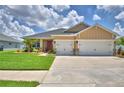 Beautiful single-story home with a two-car garage, lush green lawn, and lovely desert landscaping at 421 Riders Loop, Auburndale, FL 33823