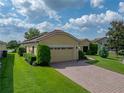 One-story home featuring well-manicured lawn, lush landscaping, and a brick driveway at 4356 Ashton Club Dr, Lake Wales, FL 33859