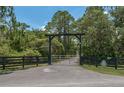 Gated entrance leading to the property, surrounded by mature trees and greenery at 4949 Lake Kotsa Dr, Lake Wales, FL 33898