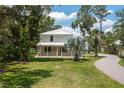 Charming two-story home with a metal roof, inviting front porch, and lush landscaping at 4949 Lake Kotsa Dr, Lake Wales, FL 33898