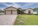 Inviting home featuring a two-car garage, neutral paint, stone accents, and a long, patterned paver driveway at 607 S 16Th St, Haines City, FL 33844