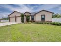 Inviting home featuring a two-car garage, neutral paint, stone accents, and a well-maintained lawn at 607 S 16Th St, Haines City, FL 33844