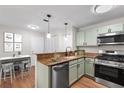 Virtually staged galley kitchen featuring granite countertops, stainless steel appliances, and wood floors at 703 Magnolia Pl # 703, Winter Haven, FL 33884