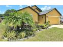 Charming exterior view showcasing the lush garden and attached two car garage at 830 Cabaret Ct, Kissimmee, FL 34759