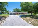 Traditional brick home with a long driveway, mature trees, and a well-maintained lawn at 961 Oleander Se Dr, Winter Haven, FL 33880