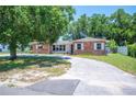 Attractive brick home featuring a lush front yard with mature trees and a well-paved driveway at 961 Oleander Se Dr, Winter Haven, FL 33880