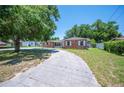 Cozy brick home with white-trimmed windows, a spacious driveway, and lush green landscaping at 961 Oleander Se Dr, Winter Haven, FL 33880