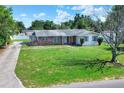Front exterior of a charming home featuring a large lawn, brick accents, and well-maintained landscaping at 961 Piedmont Se Dr, Winter Haven, FL 33880