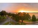 A gorgeous sunrise illuminates a vast lake, framed by mature trees, creating a serene vista at 208 Lake Howard Nw Dr # 104, Winter Haven, FL 33880