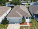 Aerial view of charming single-story home with manicured landscaping and attached two-car garage, red front door at 481 Kensington View Dr, Winter Haven, FL 33880