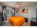 Comfortable bedroom with ceiling fan, neutral walls, and bright orange comforter at 536 Squires Grove Dr, Winter Haven, FL 33880