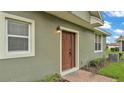 Side view of home, including a brown front door, window, and a/c unit at 6528 Sedgeford Dr, Lakeland, FL 33811