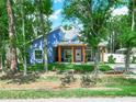 Blue home with a spacious porch, wooden beams, and a welcoming facade nestled among mature trees at 7714 Chase Rd, Lakeland, FL 33810