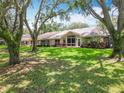 Beautiful backyard featuring a lush lawn, mature trees, and screened-in lanai at 8640 Firestone Cir, Clermont, FL 34711