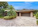 Close up of the brick home showcasing a two car garage and palm tree in the front yard at 105 Woden Way, Winter Haven, FL 33884
