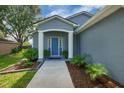 Inviting home entrance with a blue front door, white columns, and a well-manicured landscape at 124 Eagle Point Blvd, Auburndale, FL 33823