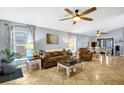Spacious living room featuring neutral tile floors, ceiling fans, and abundant natural light from the windows at 124 Eagle Point Blvd, Auburndale, FL 33823