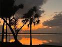 Scenic waterfront view featuring a vibrant sunset over a tranquil lake, with palm trees silhouetted at 1805 S Lake Reedy Blvd, Frostproof, FL 33843