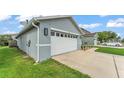 Side view of a light-grey house with an attached garage and a well-maintained lawn at 2602 Whitewood Rd, Mulberry, FL 33860