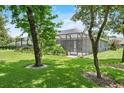 Lush backyard featuring a screened-in lanai, mature trees, and well-maintained landscaping at 2988 Sequoyah Dr, Haines City, FL 33844