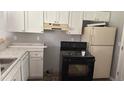 Functional kitchen featuring white cabinets, marble countertops, and black appliances at 300 E Washington St, Minneola, FL 34715