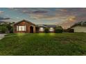 Charming brick home features a well-manicured lawn, crisp white shutters, and solar panels at 326 Sunset Rd, Frostproof, FL 33843