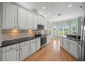An open kitchen boasts stainless appliances, granite counters, wooden floors, and white cabinets at 4254 Berwick Dr, Lake Wales, FL 33859