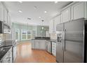 Well lit kitchen with stainless steel appliances, light green walls, white cabinetry, and hardwood floors at 4254 Berwick Dr, Lake Wales, FL 33859