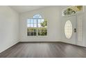 Bright entryway with wood floors, natural light from a large window, and a decorative front door at 529 Terranova Cir, Winter Haven, FL 33884