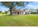 Beautiful home features a lush green lawn, charming porch with wooden pillars, and an attached garage at 5820 E Johnson Ave, Haines City, FL 33844