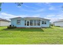 Backyard view of home featuring Florida room, well-kept lawn and landscaping at 6192 Magpie Dr, Lakeland, FL 33809