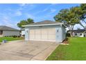 View of the two-car garage with a light blue exterior and well maintained lawn and landscaping at 6192 Magpie Dr, Lakeland, FL 33809