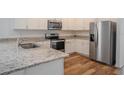 Well-equipped kitchen featuring stainless steel appliances, granite countertops, and stylish white cabinetry at 6300 Dolostone Dr, Lakeland, FL 33811