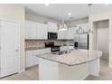 Modern kitchen features white cabinets, stainless steel appliances, and a granite island at 7247 Oakmoss Loop, Davenport, FL 33837