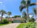 Beautifully landscaped single-story home featuring a brick driveway and tropical palm trees at 741 Canberra Rd, Winter Haven, FL 33884