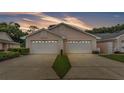Beautiful home exterior featuring two white garage doors under a stunning sunset sky at 13 Enclave Dr, Winter Haven, FL 33884