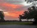 Scenic view of the community landscape at sunset, featuring an open field and scattered trees at 13 Enclave Dr, Winter Haven, FL 33884