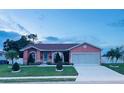 Inviting home with a lush front lawn, complemented by mature trees and a neatly paved driveway at 1366 Merrimack Pl, Davenport, FL 33837