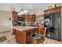 Well-lit kitchen features an island with granite countertop, dark cabinetry, and stainless steel appliances at 1366 Merrimack Pl, Davenport, FL 33837