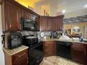 Functional kitchen featuring dark wood cabinets, granite countertops, and modern black appliances at 1366 Merrimack Pl, Davenport, FL 33837