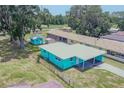 Aerial view of a turquoise home with a carport, sheds, and surrounding greenery at 2125 Hillcrest Rd, Auburndale, FL 33823