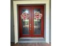 Front door with double doors and wreaths with glass panes surrounded by a light frame at 25863 Crossings Bluff Ln, Sorrento, FL 32776