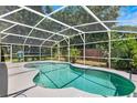 Screened in Kidney shaped pool surrounded by lush landscaping and concrete patio at 2861 Pond View Dr, Haines City, FL 33844