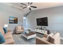 Staged living room with vaulted ceiling, modern furniture, TV, stylish rug, and wood-look flooring at 411 Red Hawk Loop, Winter Haven, FL 33880