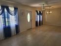 Sun-lit living room featuring tile floors, elegant curtains, and a classic chandelier, perfect for relaxation at 514 7Th S St, Dundee, FL 33838