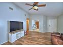Spacious living room showcasing hardwood floors, a ceiling fan, and large television at 658 Lake Dexter Cir, Winter Haven, FL 33884