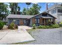Cozy one-story home with a charming wooden porch, gravel driveway, and lush landscaping at 103 Se Tuscawilla Ave, Ocala, FL 34471