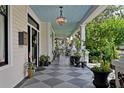 Inviting front porch with a decorative chandelier, checkered flooring, and lush potted plants at 103 Se Tuscawilla Ave, Ocala, FL 34471