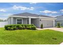 Well-maintained gray home features a lush green lawn and an attached garage at 1976 Harvest Landing Cir, Lakeland, FL 33810