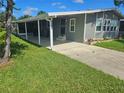 View of the home's side entrance and a covered patio area, enhanced by verdant lawn at 6685 Briarhill Dr Ne, Winter Haven, FL 33881